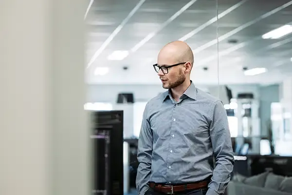 Een adviseur van Infodatek Group staat in het kantoor, tussen de werkplekken.