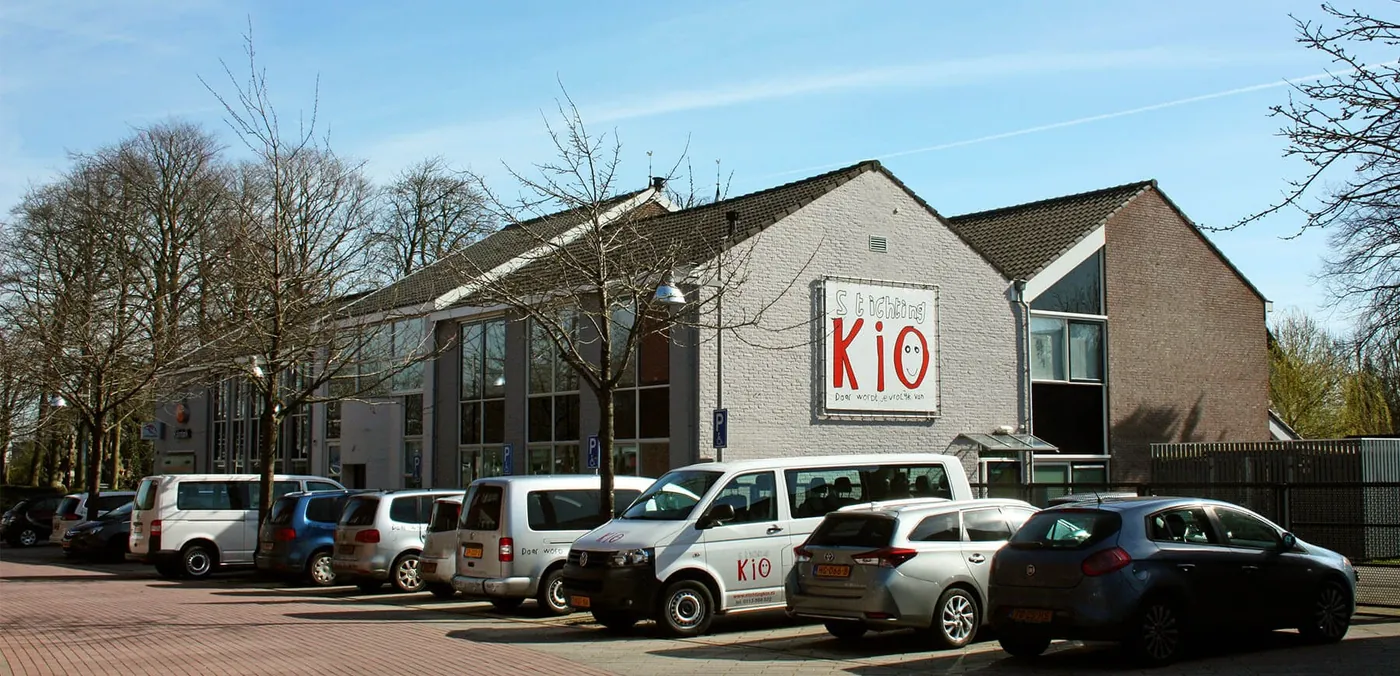 Het gebouw van Stichting KIO met geparkeerde auto's ervoor.
