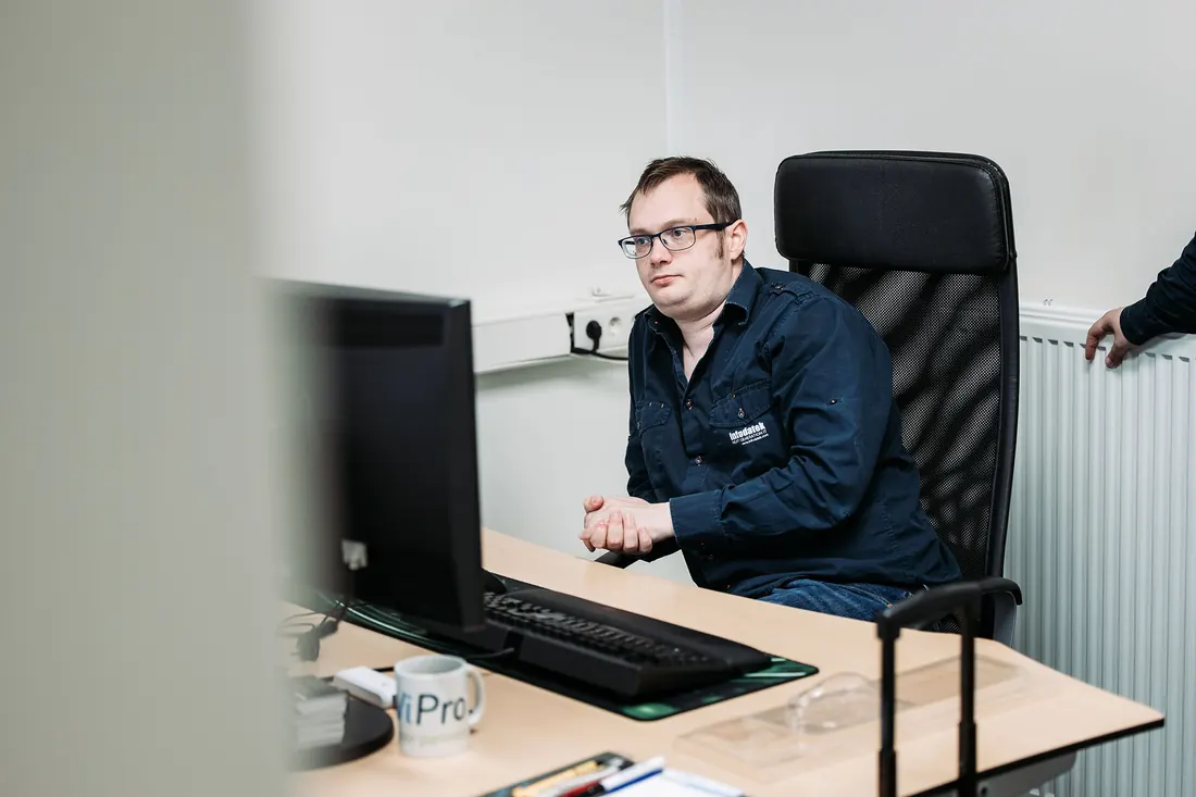 An Infodatek Group engineer wearing glasses at his desk, behind his screen.
