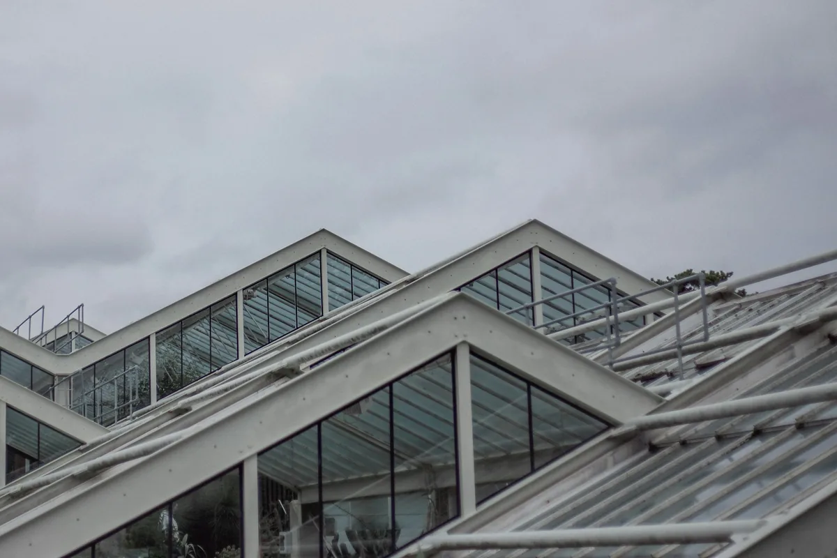 Glazen daken van een kassencomplex onder een grijze lucht.