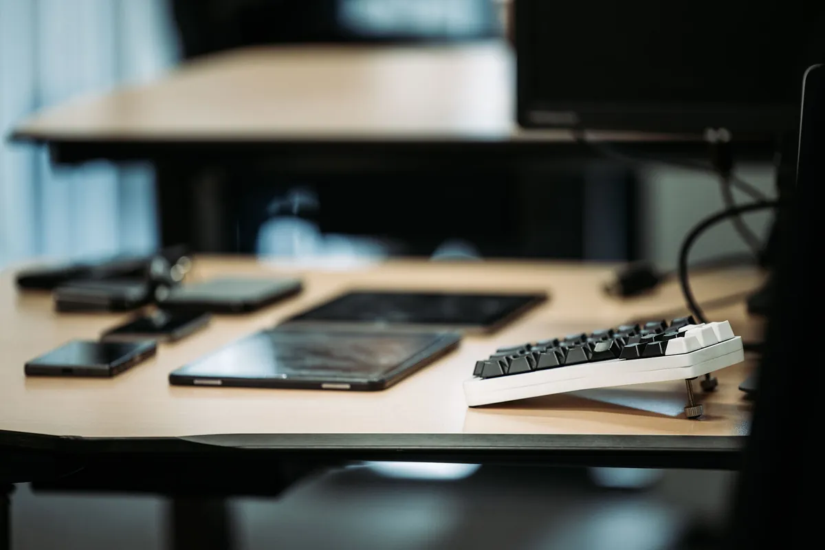 A tidy workplace at Infodatek Group with laptop, phone and keyboard.
