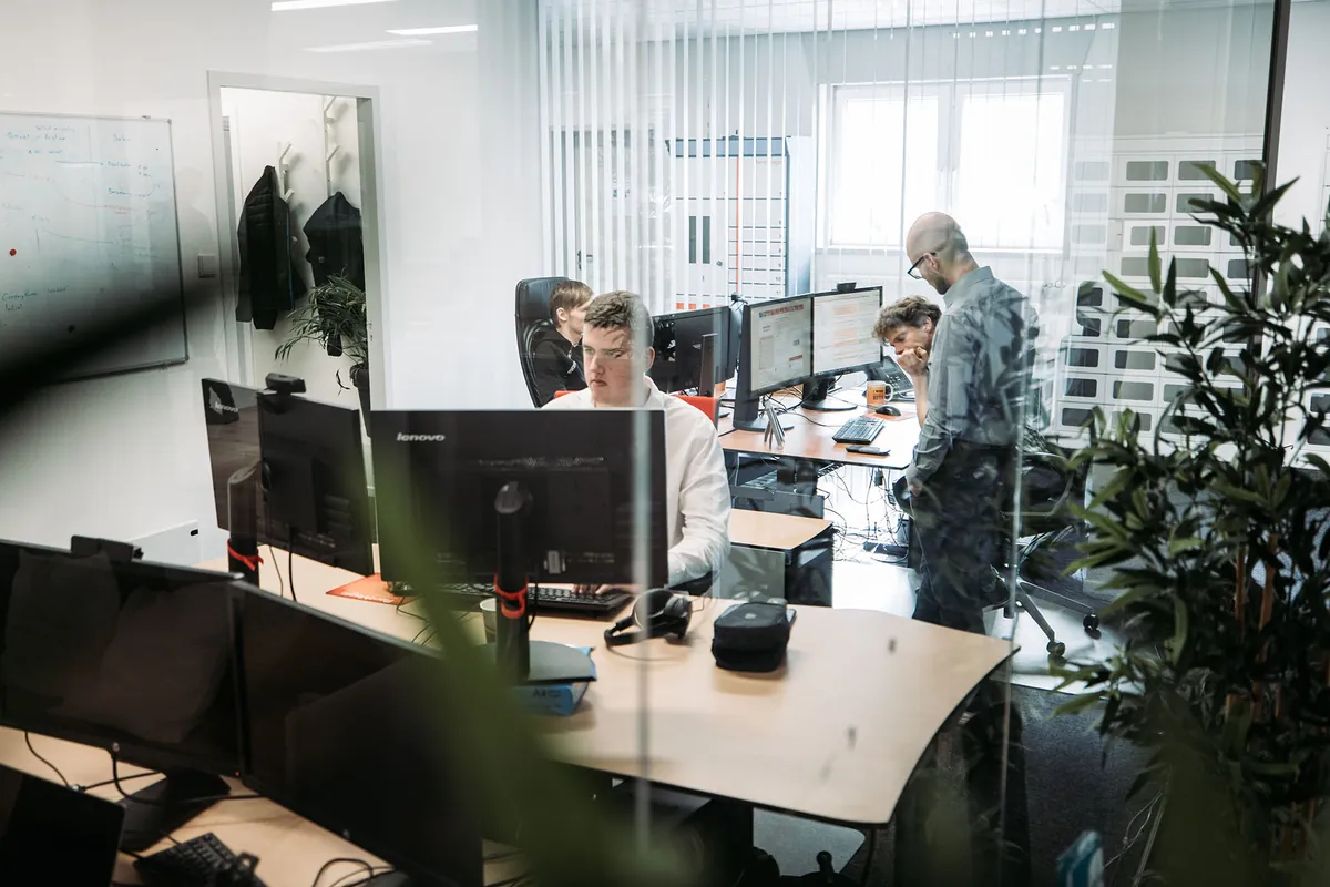 Infodatek Group colleagues at their workplaces in a bright office.